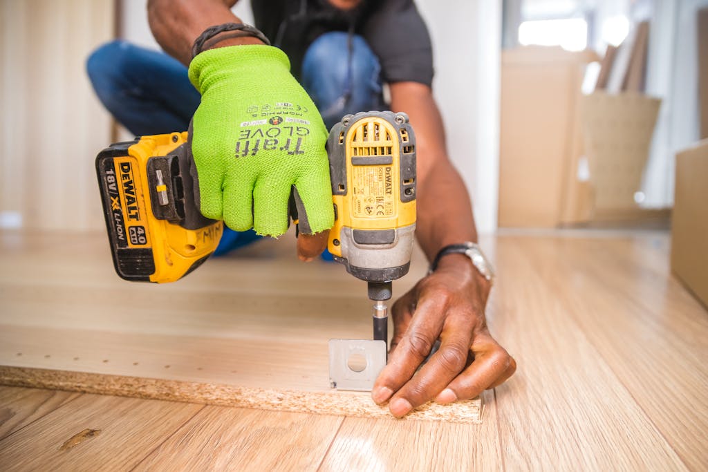 photo by bidvine Man using a power drill for home improvement on a wooden floor with precision.