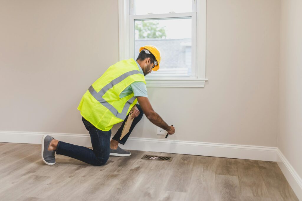 pexels photo 8292797 8292797 Worker in safety gear inspecting a room's corner for renovation or improvement.